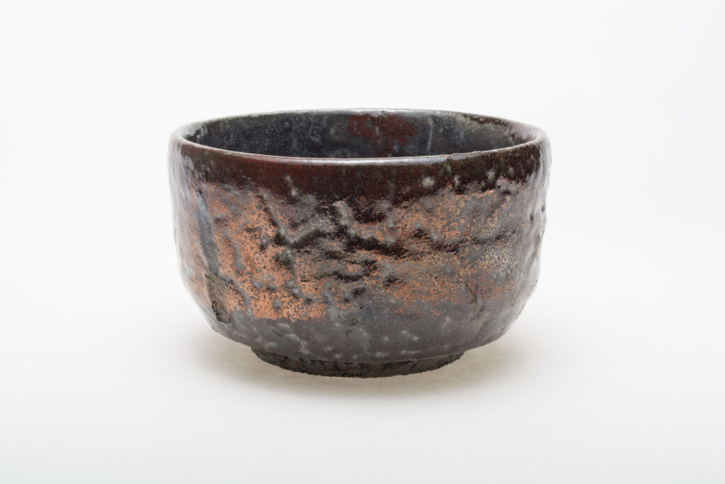 A Raku bowl by artist Nick De Pirro with copper penny glaze combined with other low fire glazes, reduced in leaves.